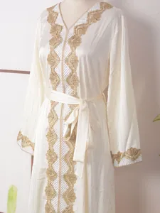Detalle de encaje dorado y bordado de pedrería en un vestido de fiesta color crema.