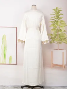 Vista trasera de elegante vestido maxi crema con puños de encaje dorado