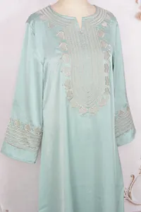 Détail d'une robe caftan brodée vert menthe avec dentelle argentée complexe sur le décolleté