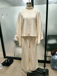 Cream-colored two-piece lounge set featuring a high-neck top and wide-leg trousers