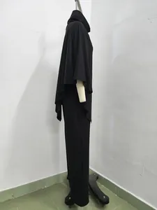 Side profile of a black two-piece set with a hooded cape top and wide-leg trousers.