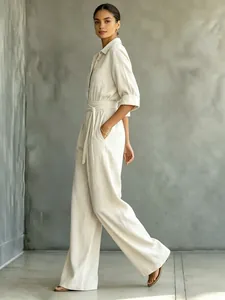Full-body shot of a chic beige half-sleeve wide-leg jumpsuit with waist tie detail.