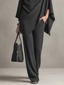 Elegant black two-piece set featuring a draped poncho top and matching wide-leg trousers