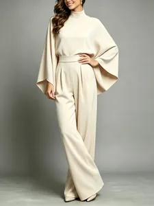 Full body model shot showing the flowy cape sleeves and tailored wide-leg cream trousers