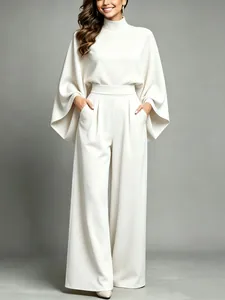 Close-up of elegant cream high-neck two-piece set with cape sleeves and wide-leg pants