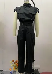 Dettaglio di una tuta nera da donna a vita alta con cintura decorativa e spalline.