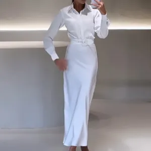Vue détaillée des manches longues élégantes et de la ceinture assortie de cette robe polo blanche