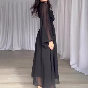 Detail showing the elegant mesh sleeve and flowy silhouette of the black dress