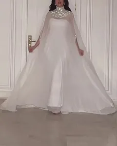 Elegante witte maxi-jurk met een glinsterende cape van lovertjes en een hoge split