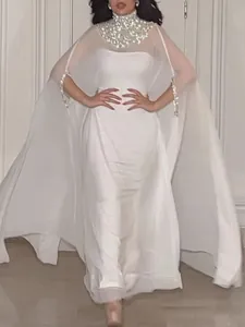 Elegante witte maxi-jurk met metalen pailletten halslijn en vloeiende cape detail.