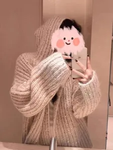 Primo piano di un cardigan beige con cappuccio in maglia e discreti decori in paillettes