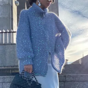 Dettaglio del cardigan in maglia blu con paillettes luccicanti e cerniera argento.