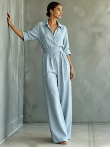 Full body view of a light blue wide-leg jumpsuit with a shirt collar and tied waist.