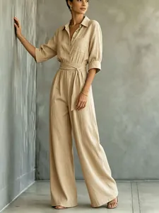 Detail shot of beige linen jumpsuit featuring collared top and belted wide legs
