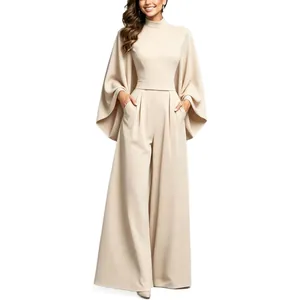 Elegant beige mock neck jumpsuit with dramatic cape sleeves and wide-leg trousers.
