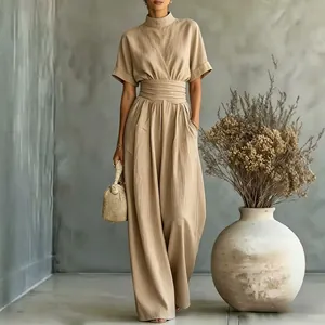 Detail view of a beige high-neck short-sleeve wide-leg jumpsuit with belted waist