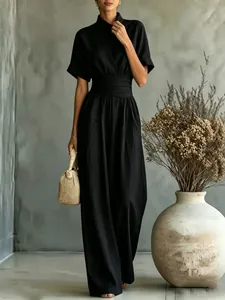 Elegant black high neck jumpsuit with short sleeves and wide legs, styled with a woven bag.