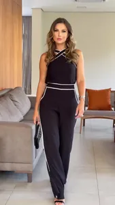Detail view of woman wearing a black halter neck two-piece set with white piping