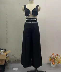 Full view of black vest and wide-leg trousers set with white contrast piping details.