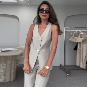 Dettaglio di un completo gilet senza maniche e pantaloni beige con bottoni dorati.
