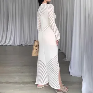 Vue arrière d'une robe longue blanche en maille ajourée sur modèle dans un studio avec rideau