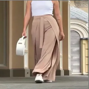 Elegante beige weite Hosenrock mit Gürtel, präsentiert von Model im Freien