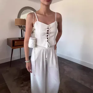 Weißes Set bestehend aus einem Schnürtop und einer eleganten Hose mit weitem Bein