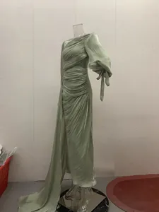 Detail van de mintgroene gedrapeerde one-shoulder avondjurk met zijsplit en pofmouw