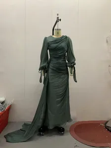 Elegante donkergroene geplooide maxi-jurk met lange mouwen op een etalagepop getoond