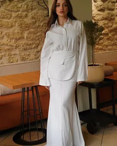 Detailed view of an elegant white three-piece set featuring a long-sleeve shirt and maxi skirt