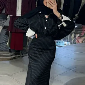 Detail of pinstriped long-sleeved shirt and hip-hugging maxi skirt set with white cuffs