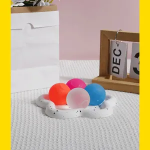Vue détaillée de quatre balles anti-stress colorées sur un plateau décoratif en fleur
