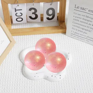 Détail montrant trois balles anti-stress pailletées roses sur un plateau blanc