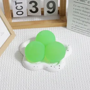 Détail de trois balles anti-stress vert malto sur un plateau fleuri tacheté blanc