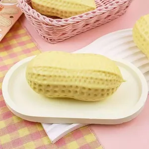 Gros plan d'un jouet squishy en forme de cacahuète sur un plateau blanc et rose.