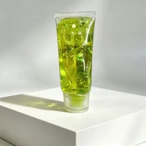 Détail d'un tube de jouet squishy avec du gel vert et des paillettes étincelantes en étoile.