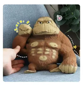 Close-up of a brown muscular gorilla squeeze toy being hand-pinched on a blue sofa
