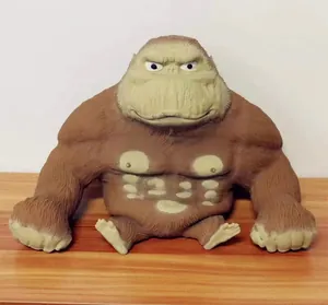 Funny muscular gorilla toy with grumpy face sitting on a wooden surface for relief