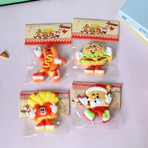 Close-up of four cartoon food-themed squeeze toys in packaging on a pink surface.