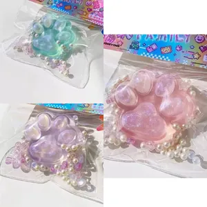 Κοντινό πλάνο με τρία γυαλιστερά παιχνίδια squishy πατούσα γάτας σε ροζ, μωβ και πράσινο