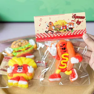 Detail shot of a cartoon hot dog squeeze toy in plastic packaging held by a hand