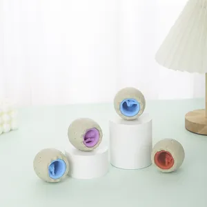 Colorful dinosaur egg squeeze toys on white display pedestals in a bright setting.