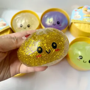 Gros plan d'un jouet squishy en forme de pain doré à paillettes tenu dans la main