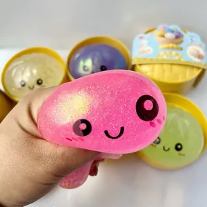 Gros plan d'un jouet squishy rose pailleté en forme de brioche souriante pressée à la main
