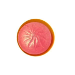 Gros plan d'un jouet anti-stress baozi rose pailleté dans un petit bol orange vif