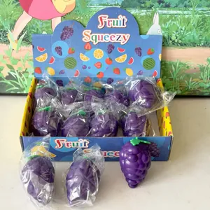 Gros plan de jouets à presser en forme de raisin violet remplis de farine en boîte.