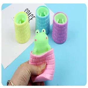 Hand drückt ein rosa Frosch-Spielzeug, um den grünen Frosch zur Entspannung zu zeigen