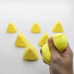 Detailed view of hand squeezing a slow rebound yellow cheese-shaped stress relief toy