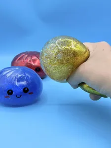 Gros plan d'une main serrant un jouet anti-stress en forme de boulette dorée à paillettes
