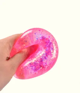 Gros plan d'un jouet anti-stress rose pailleté rempli de maltose pressé à la main